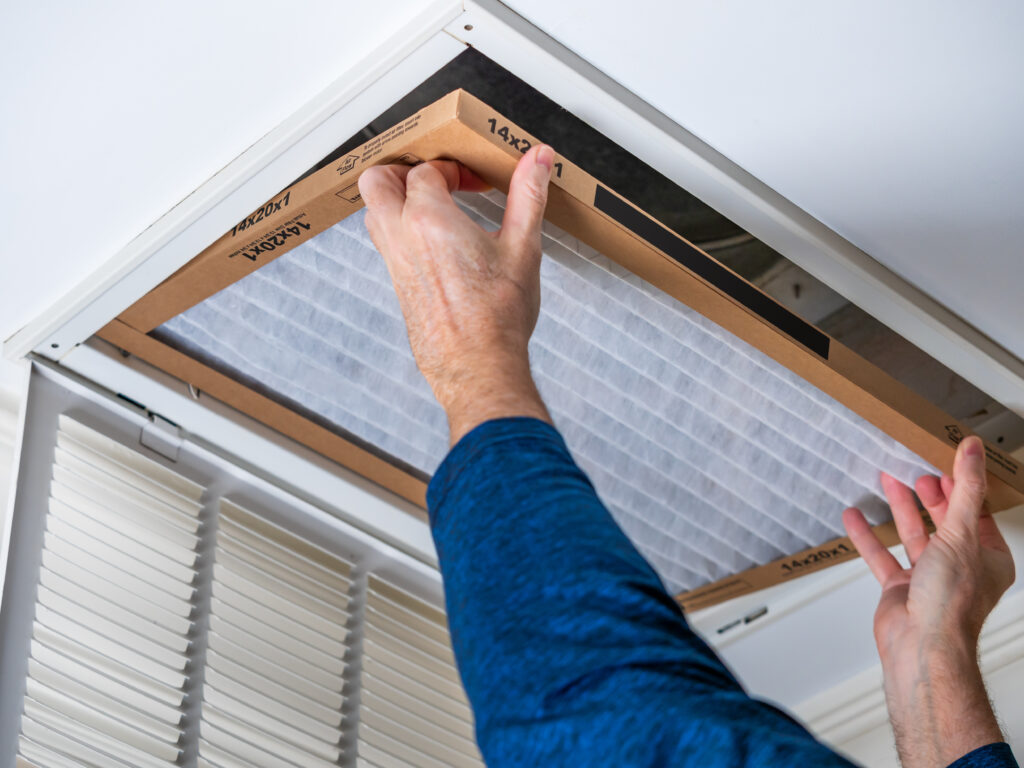 HVAC technician replacing a home air filter in Bellflower